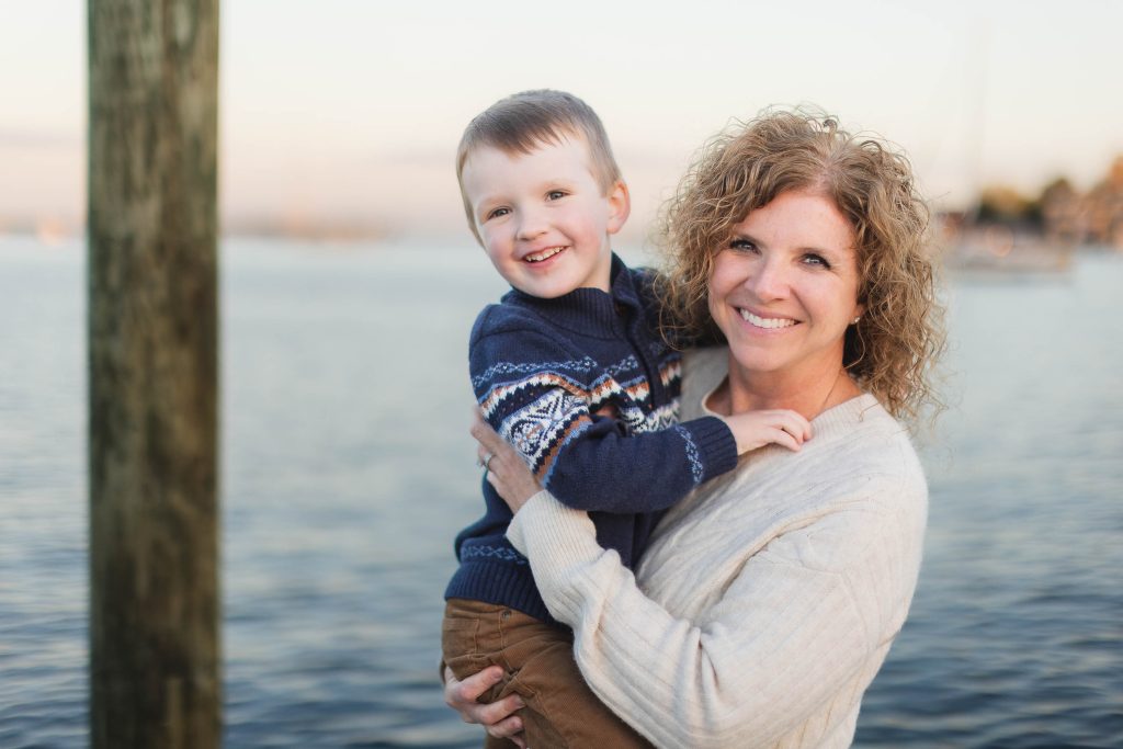 A woman holding a young boy in front of a dock in Downtown Annapolis, Maryland.