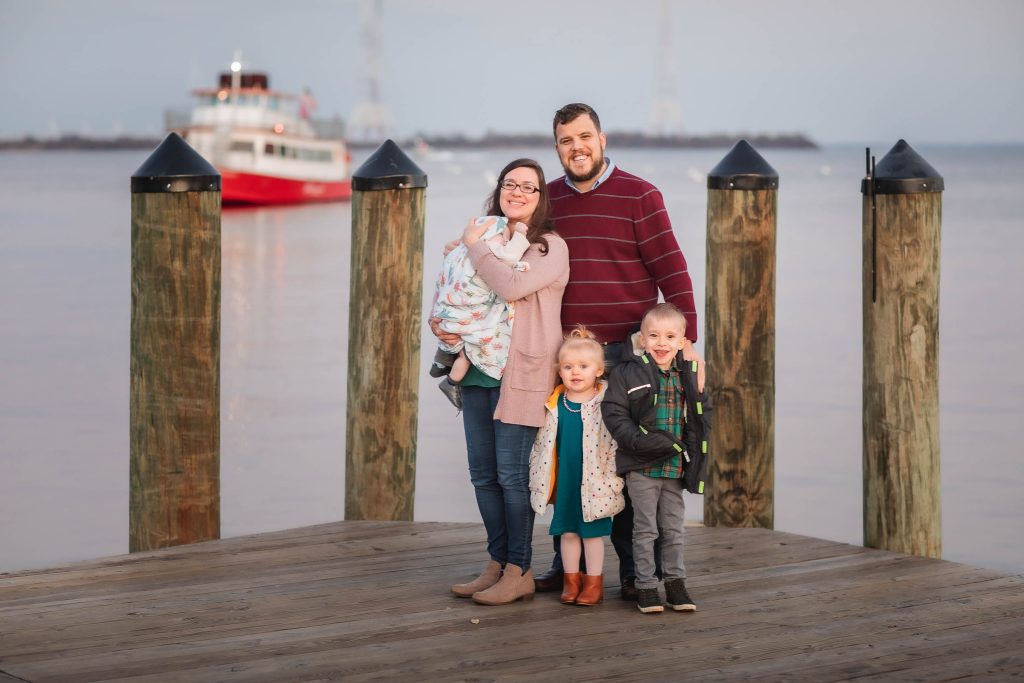 A family poses on a dock in downtown Annapolis, Maryland, with a boat in the background.
