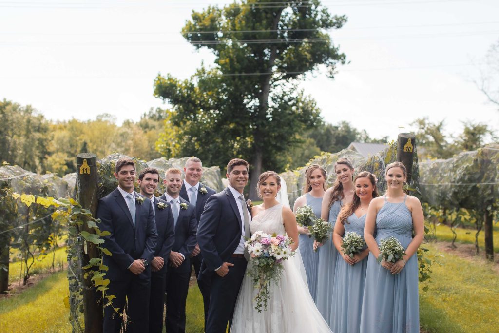 A group of bridesmaids and groomsmen pose for a photo at the Fleetwood Farm Winery in Virginia.