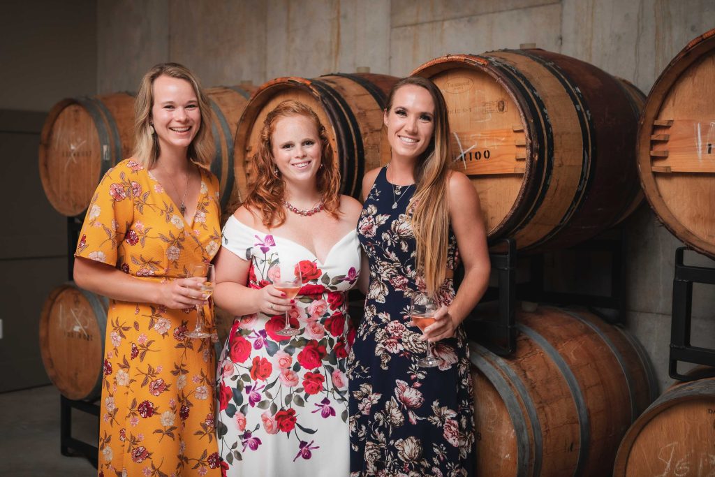 Three women standing in front of wine barrels at Fleetwood Farm Winery, Leesburg.