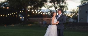 A couple at Leesburg, Virginia's Fleetwood Farm Winery posing in front of a string of lights.