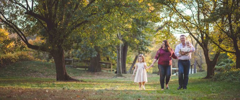 A family walks through Fort Ward Park in Virginia during the fall.