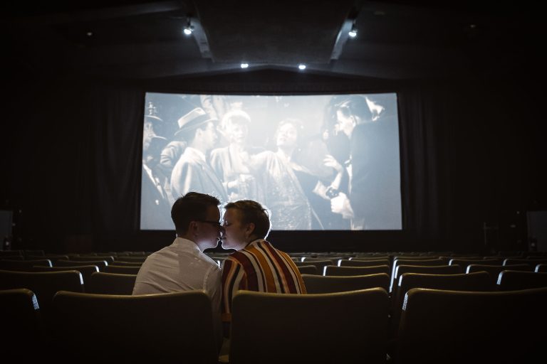 A couple kissing in front of the Old Greenbelt Theatre in Maryland.