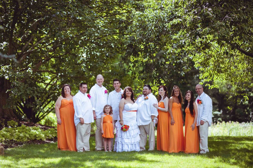 A wedding party in orange dresses posing for a photo at Historic London Town & Garden in Maryland, close to Annapolis.