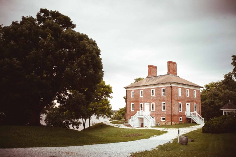 A historic red brick house sits in the middle of a grassy field near Annapolis, Maryland.