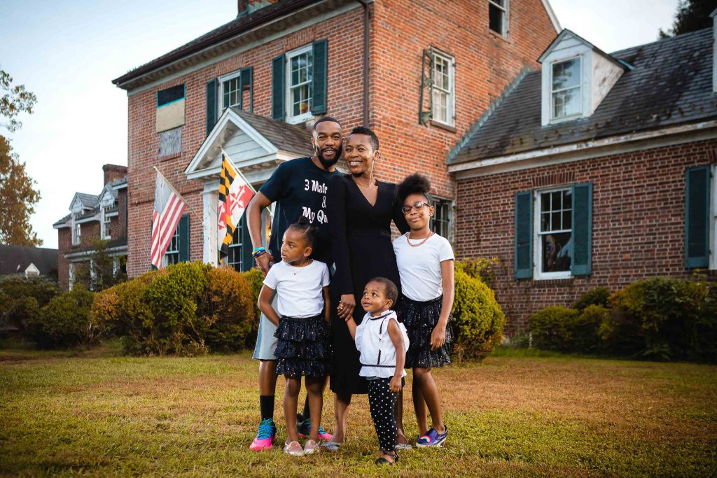 A family posing in front of a brick house in Maryland.