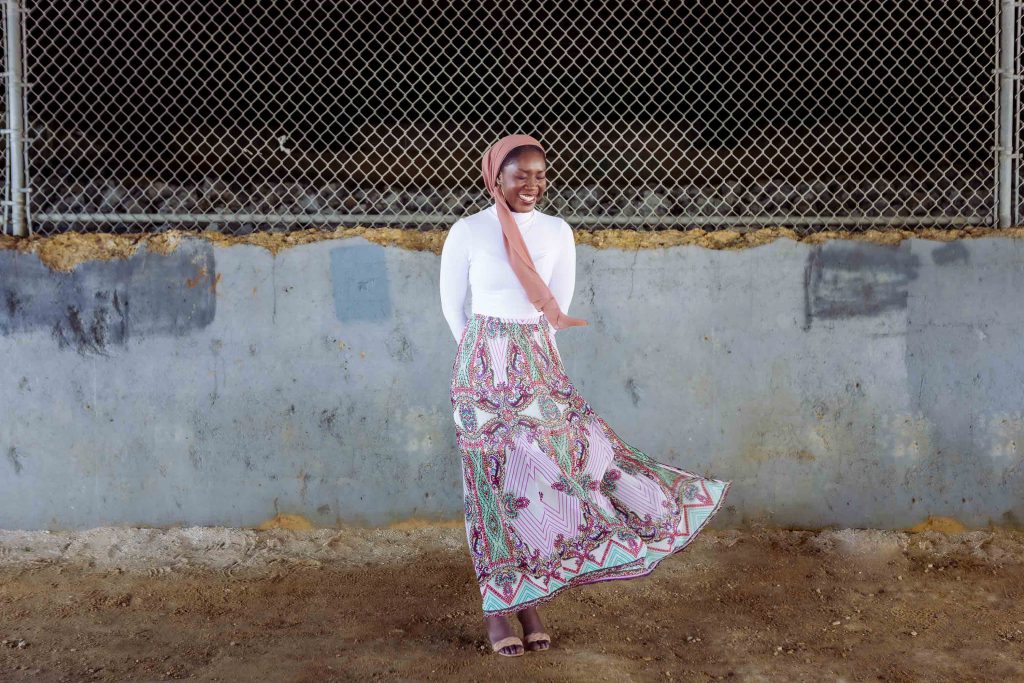 A woman in a pink skirt standing in front of a fence at Jonas and Anne Catharine Green Park in Annapolis, Maryland.