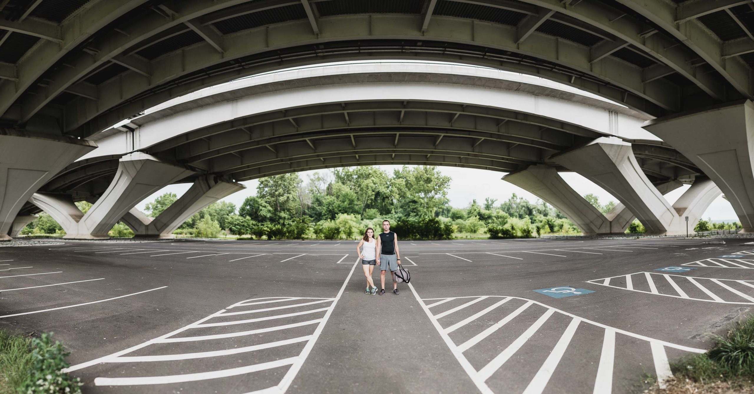 A man and woman are standing under a bridge in Jones Point Park in Alexandria, Virginia.
