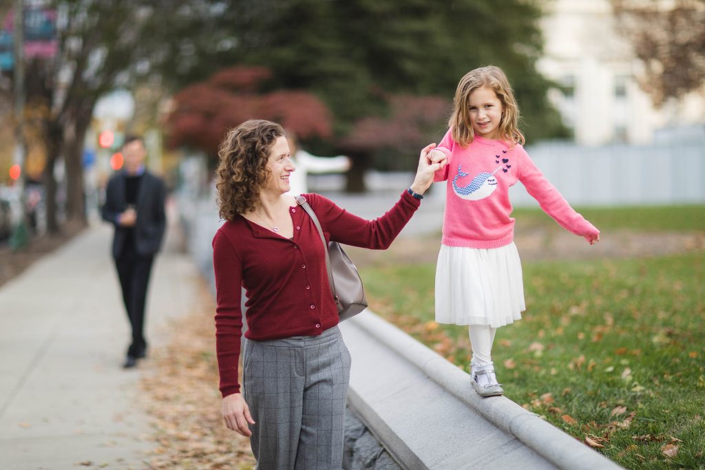 A woman and a little girl walking on a sidewalk near the Library of Congress in Washington DC.