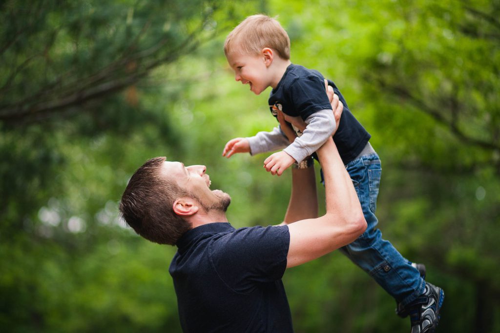 A man is holding his son up in the air at Locust Grove Nature Center in Maryland.