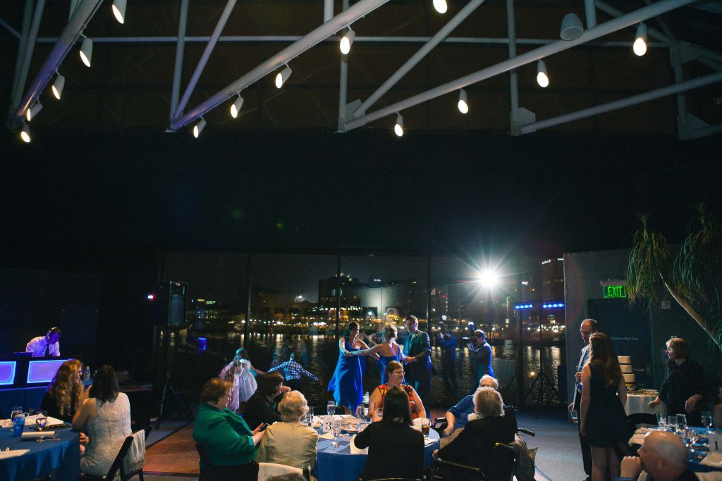 A group of people sitting at a table in a dark room at the National Aquarium.