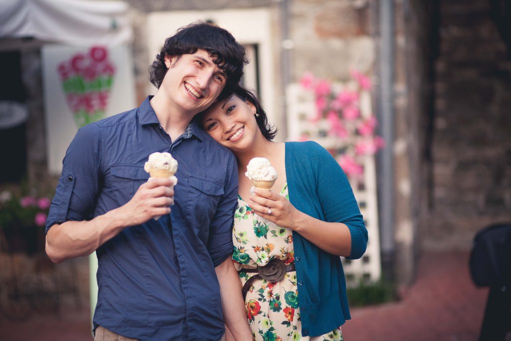 A couple holding ice cream cones in front of an old building in Ellicott City, Maryland.