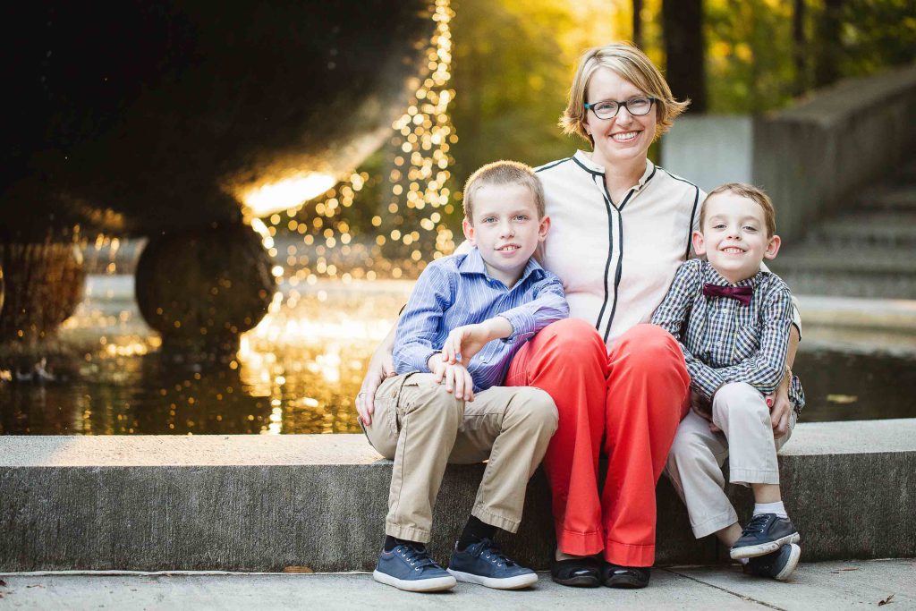 A woman and two boys sitting on steps in front of a fountain at Theodore Roosevelt Island.