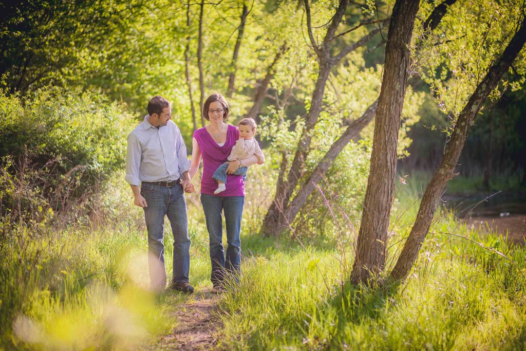 A family walks through Wheaton Regional Park with a baby in their arms.