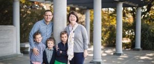 A family is posing for a photo in front of the George Mason Memorial in Washington DC.