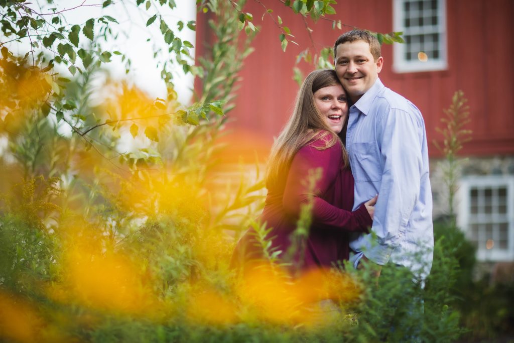 An engaged couple posing in front of a red barn in Bel Air, Maryland.