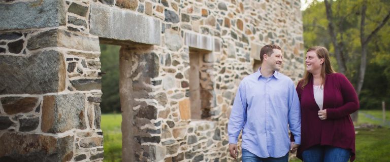 An engaged couple standing in front of a stone building in Maryland.