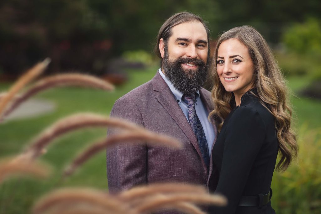 A couple posing in front of tall grasses at Rawlings Conservatory in Baltimore, Maryland.