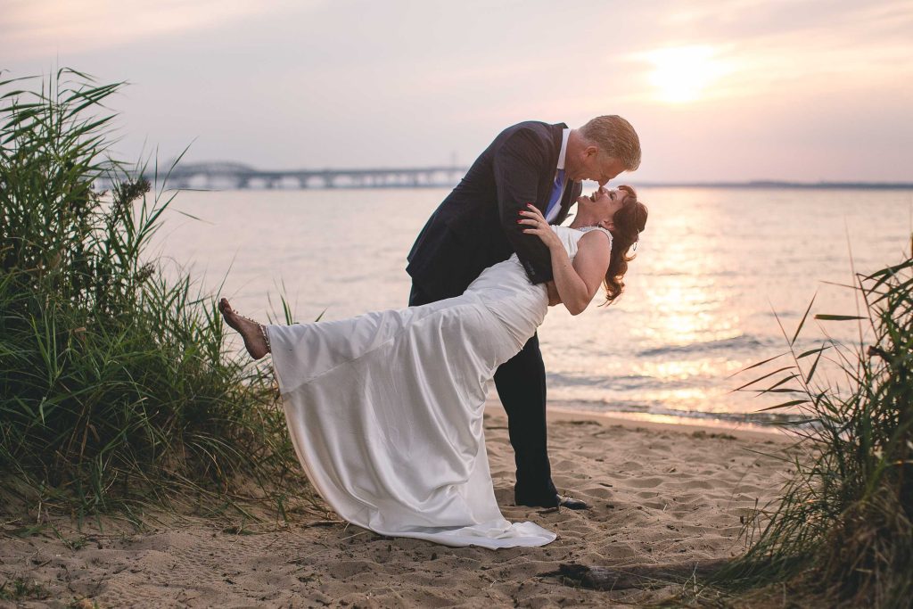 A bride and groom kiss on the beach at Terrapin Nature Park, Stevensville, Maryland.