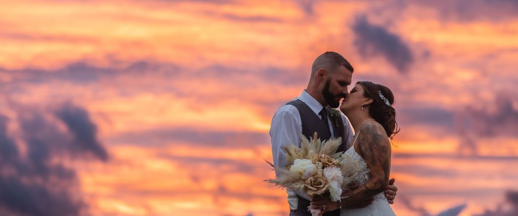 A bride and groom kiss in front of a sunset at Two Lions Vineyard in Upper Marlboro, Maryland.