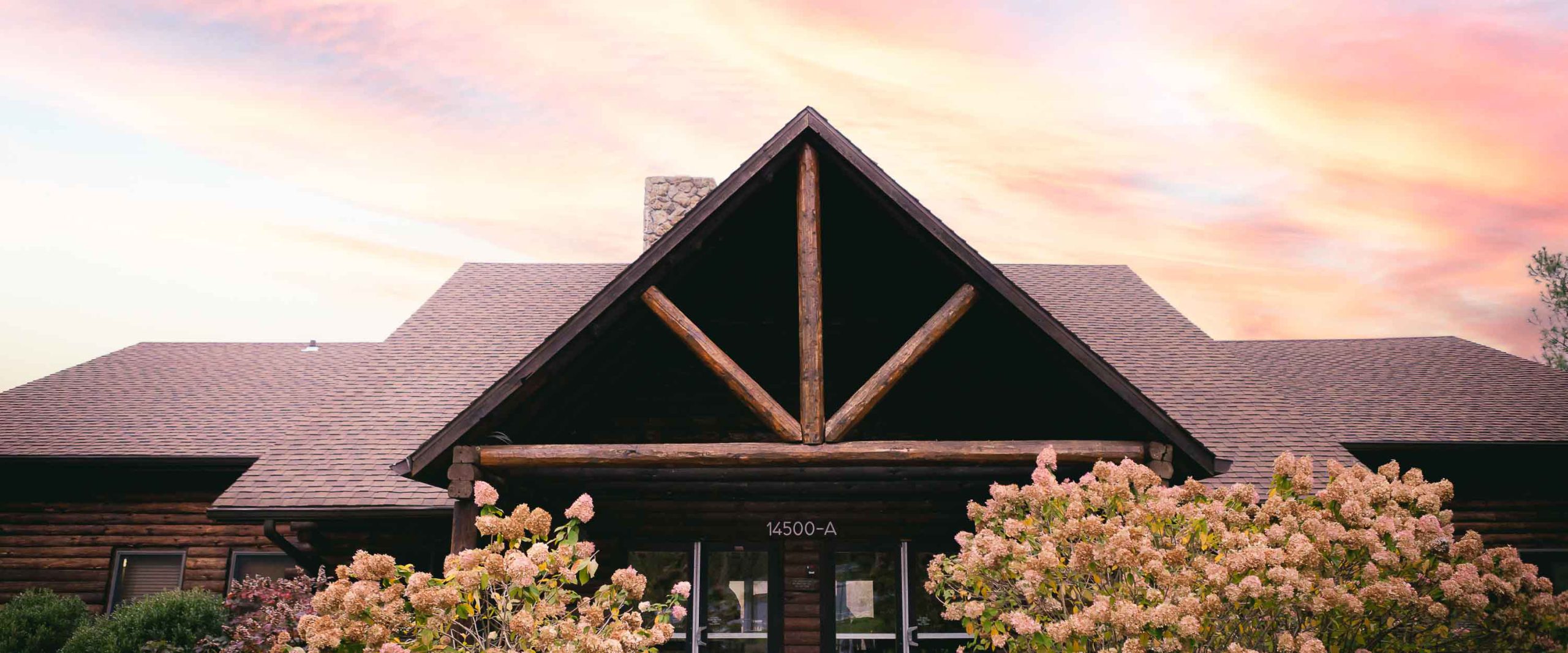 The Great Seneca Lodge facade made of dark brown timber with an orange sunset in the background. 