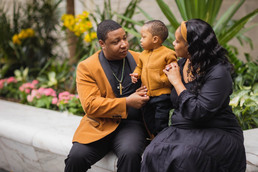 A family sits on a bench at the National Portraits Gallery, with a baby in their arms.