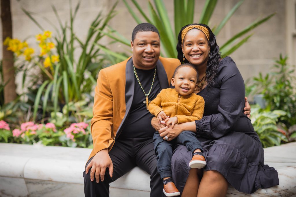 A family gathers in front of a flower garden for a photo, capturing their joyful moments together.