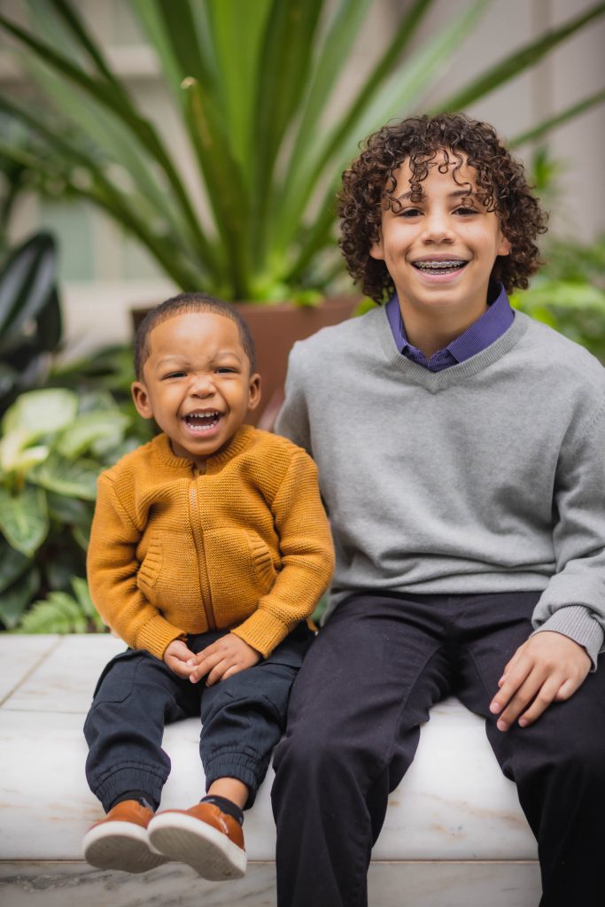 Two boys sitting on a bench in front of a plant at the National Portraits Gallery.