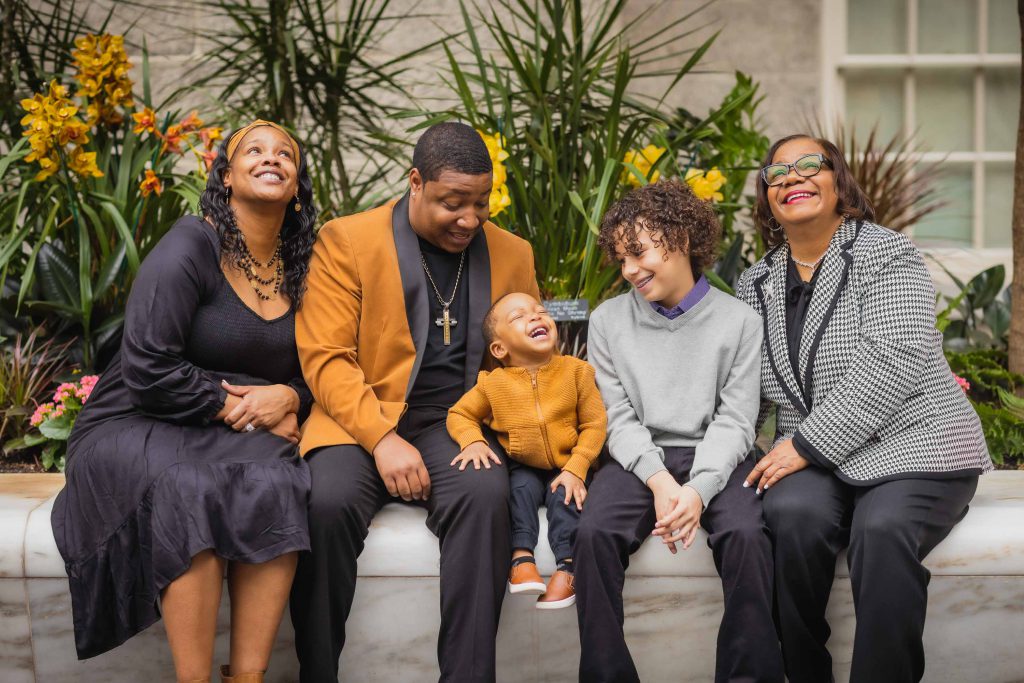 A family sits on a bench at the National Portraits Gallery and smiles.