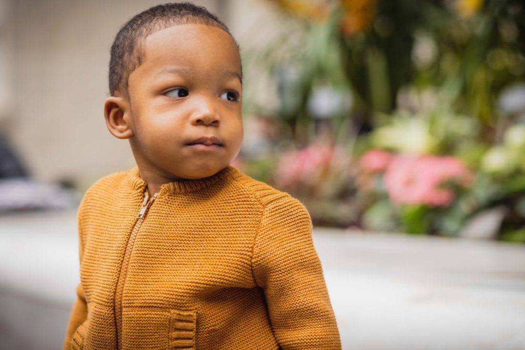 A young boy in an orange jacket is looking at the camera at the National Portraits Gallery.