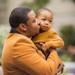 A family poses for a portrait in front of the National Portraits Gallery as a man affectionately kisses his son.