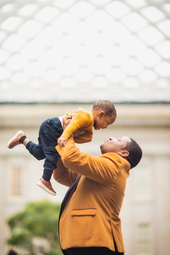 A man in the National Portraits Gallery is holding a child in the air.