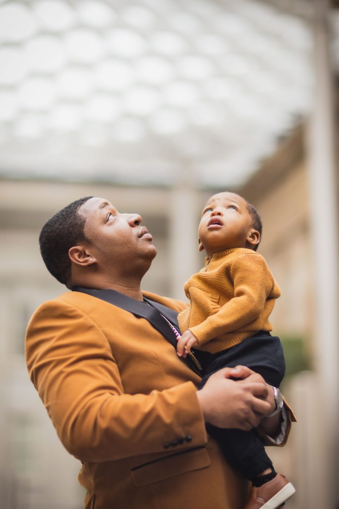 A man holding a baby in his arms at the National Portraits Gallery.