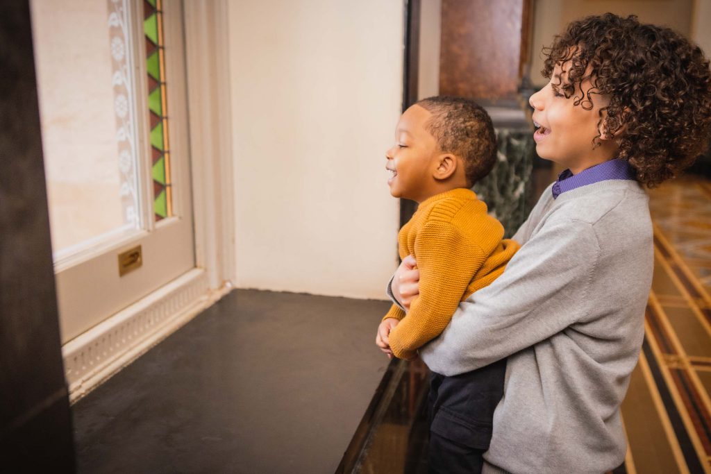 A boy and a girl from a family looking out of a window at the National Portraits Gallery.