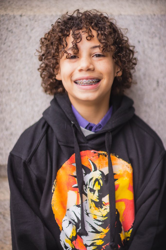 A young boy wearing a dragon ball hoodie poses for a portrait at the National Portraits Gallery with his family.