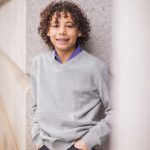 A young boy with curly hair leaning against a wall at the National Portraits Gallery.