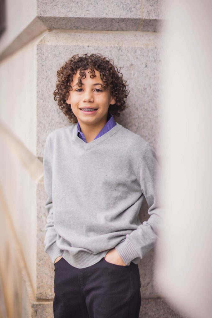A young boy with curly hair leaning against a wall at the National Portraits Gallery.