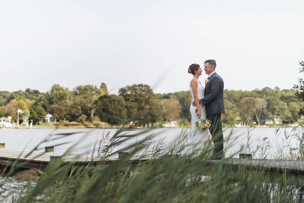 A bride and groom standing on a dock near the water at Kent Island Resort in Maryland's Stevensville.