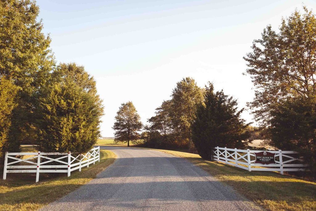 A white fence leading to a dirt road in Stevensville, Maryland.