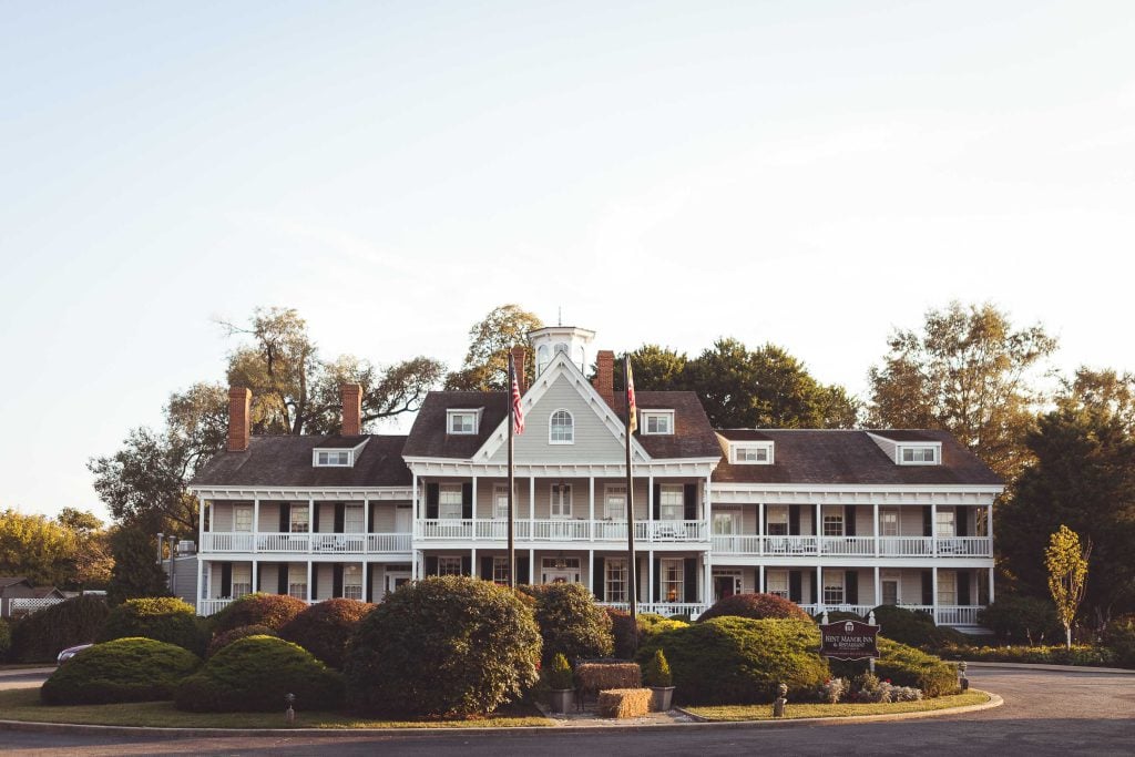 A large white house in Stevensville with bushes in front of it.