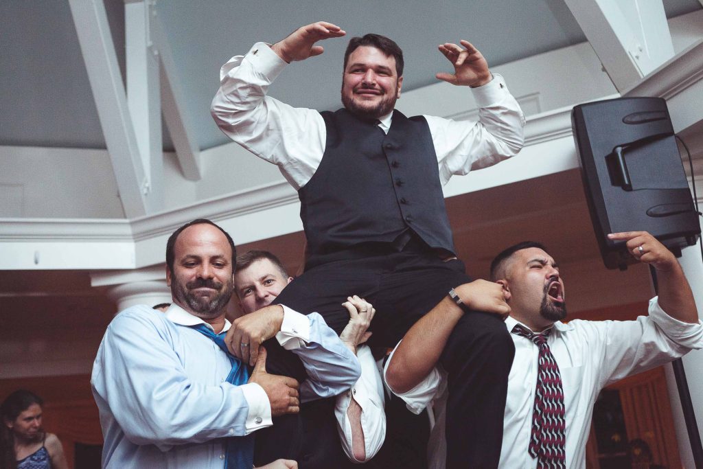 A man in a tie is holding up another man in a tie at Kent Island Resort.