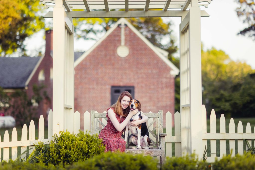 A woman sits on a bench with her dog in front of Montpelier Mansion in Maryland.