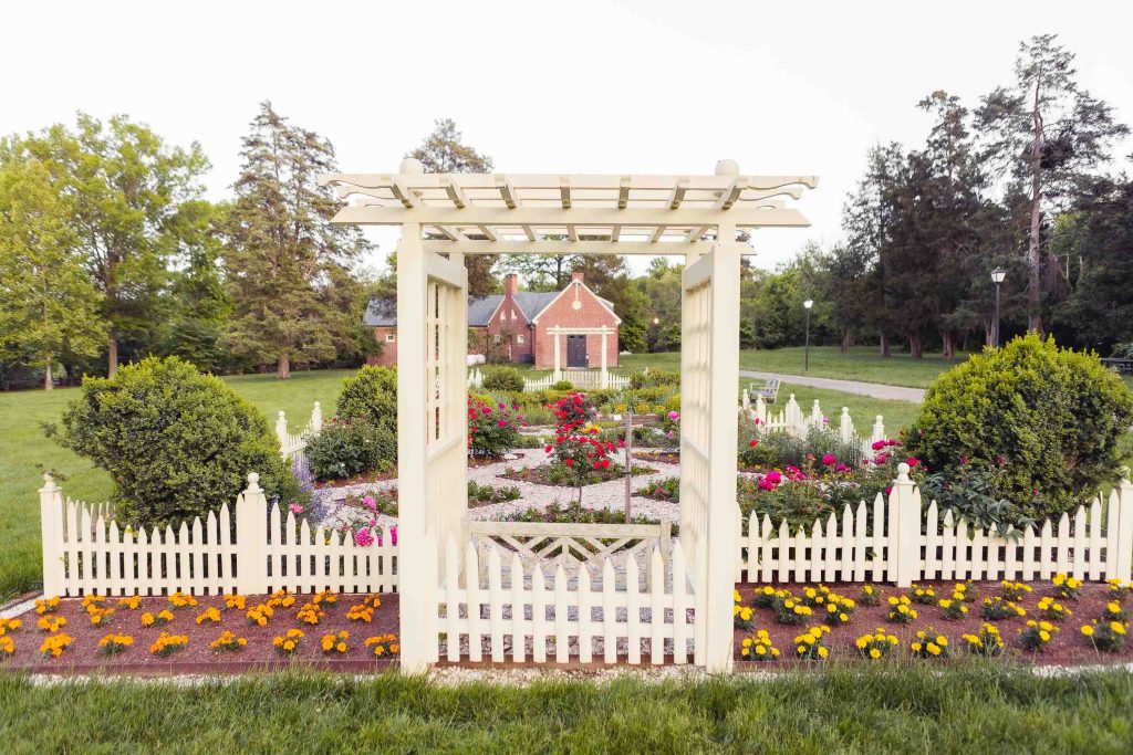 A Montpelier Mansion in Maryland with a white picket fence and flowers.