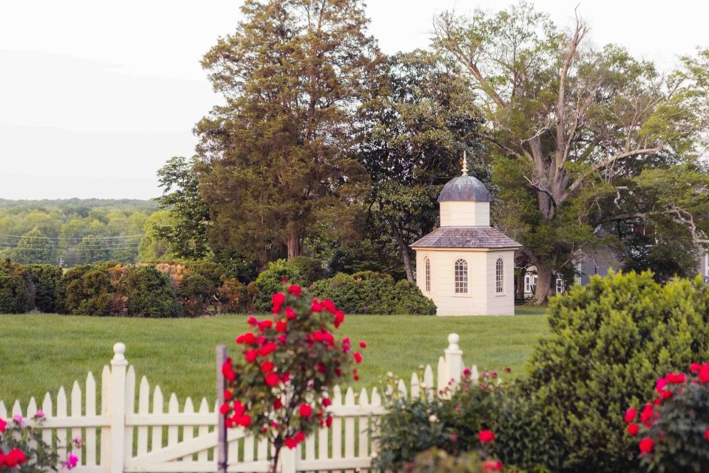 A white picket fence with roses in the background at Montpelier Mansion in Laurel, Maryland.