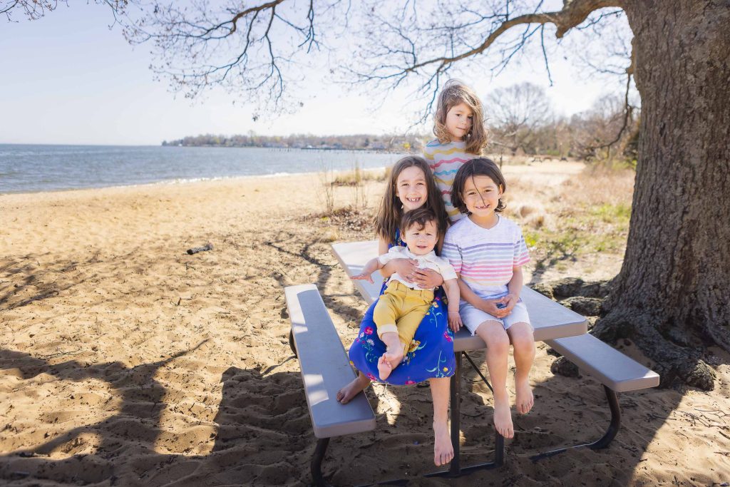 Four family members sitting on a picnic table at the beach.