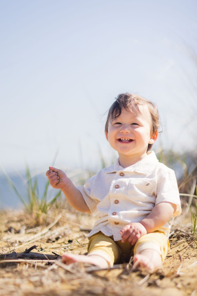 A baby sitting on the sand in Maryland, enjoying the ocean view.