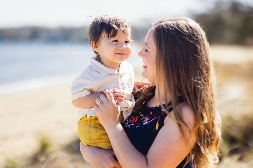 A woman holding a baby on the Annapolis beach.