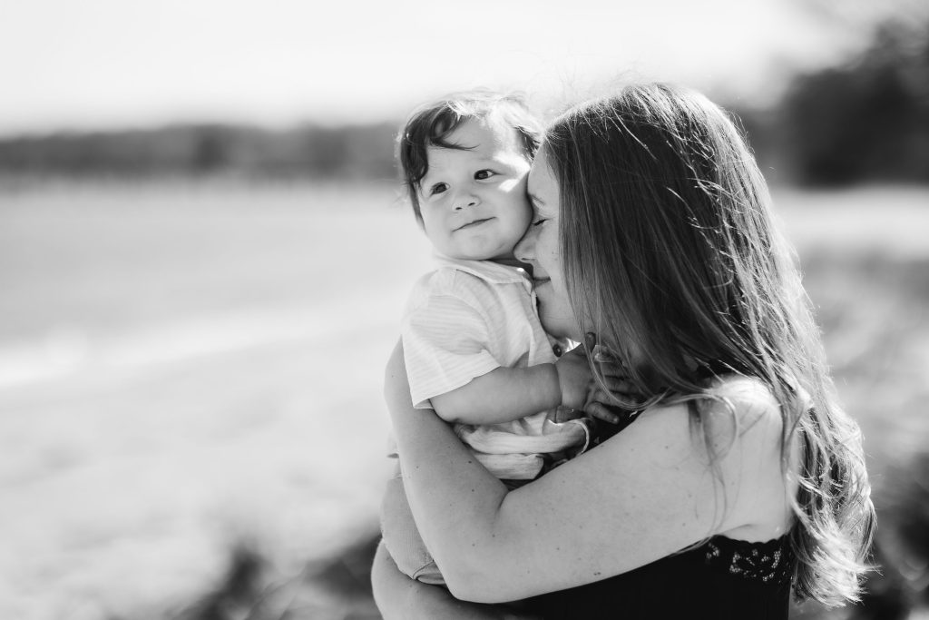 A black and white photo of a woman holding a baby on the beach in Maryland.