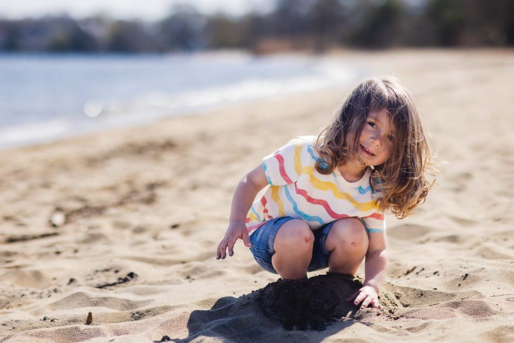 A little girl playing in the sand on the beach near Chesapeake Bay Foundation.