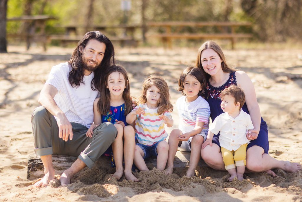 Portrait of a family sitting on a log in the sand, captured by Chesapeake Bay Foundation.